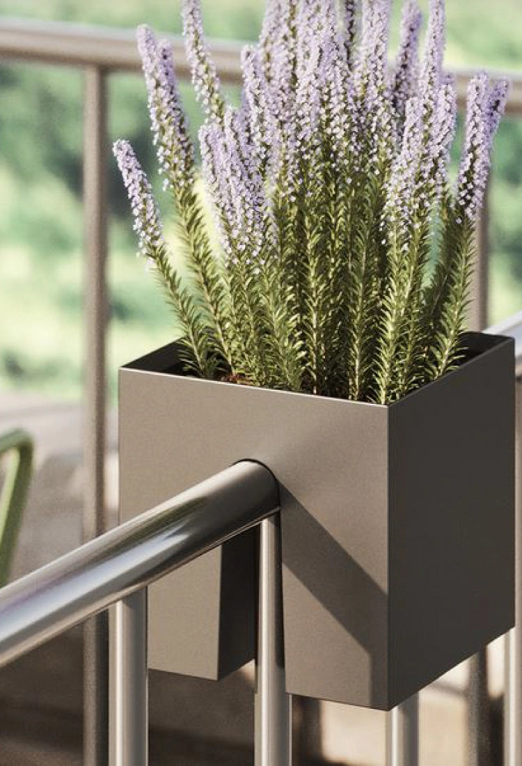Ein stilvoller Balkon verfügt über moderne Pflanzgefäße mit Lavendel und Grünpflanzen, gepaart mit einem grün gestreiften Tisch und Stühlen vor einer üppigen Kulisse.
